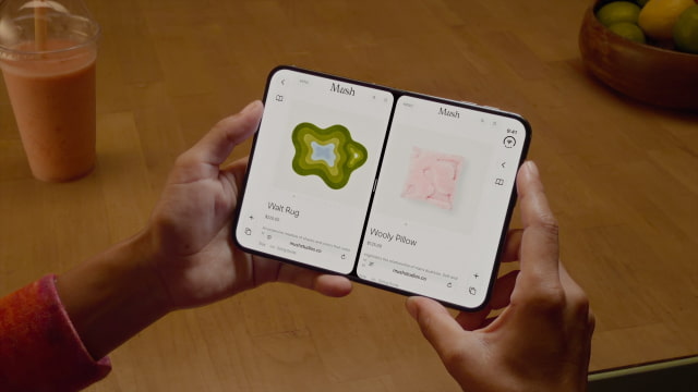 A person holds an unfolded iPhone Duo above a wooden table, with two Safari windows displayed side by side.