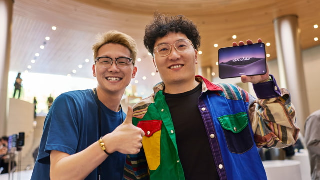 A customer holds an unfolded iPhone Duo beside an Apple team member at Apple Jing'an in Shanghai.
